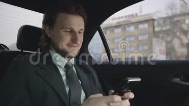 一个英俊的男人，棕色头发，穿着开心果衬衫，穿着灰色西装，坐在车里，通过手机输入信息